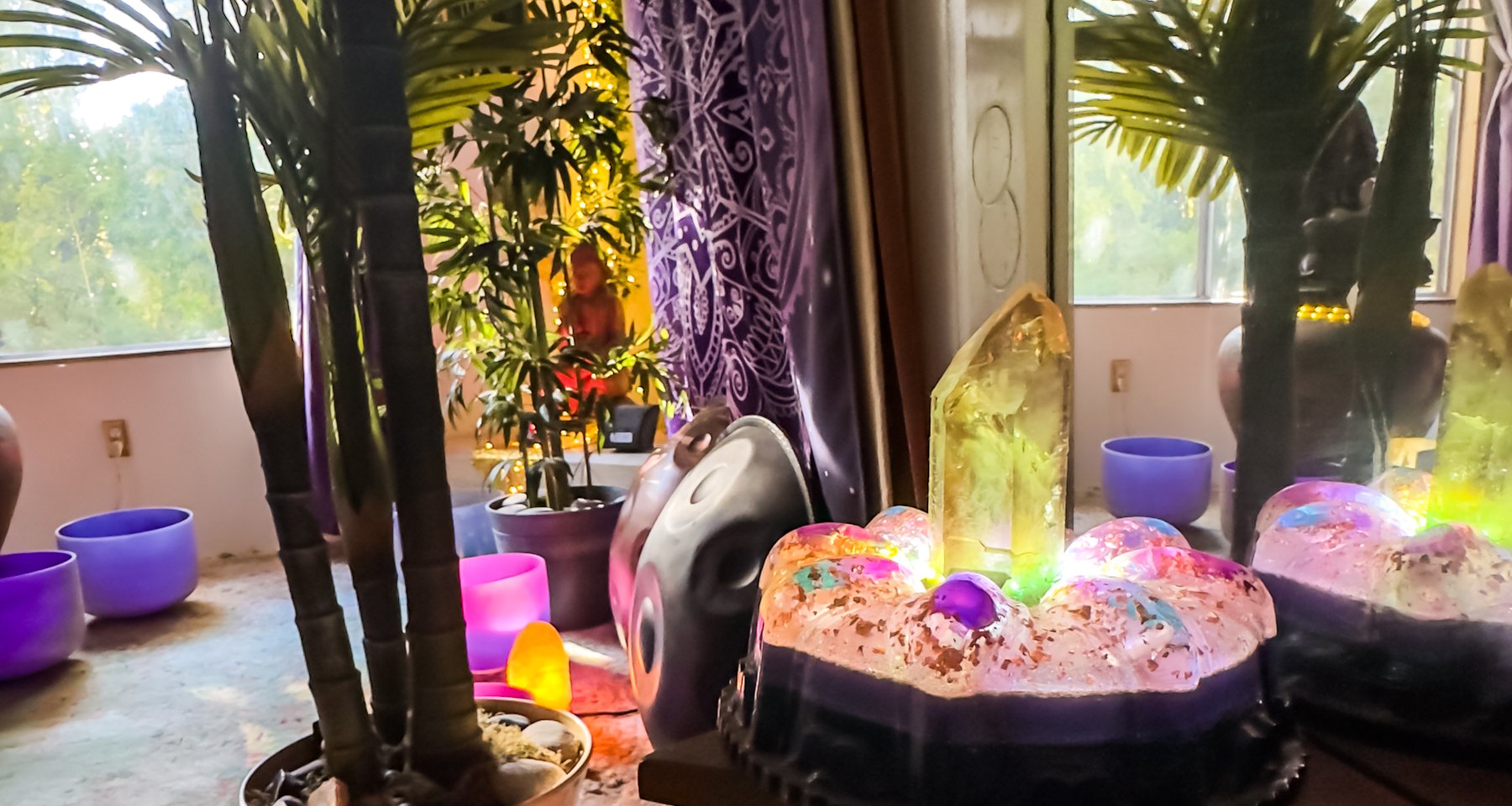 The orgonite generator up close — a citrine point rising from glowing colored spheres, the handpan behind