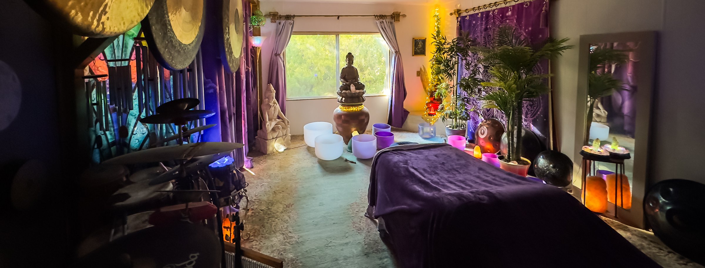 Inside the sound-healing studio — gongs, chimes and drums along one wall, crystal bowls on the floor, the massage table ready